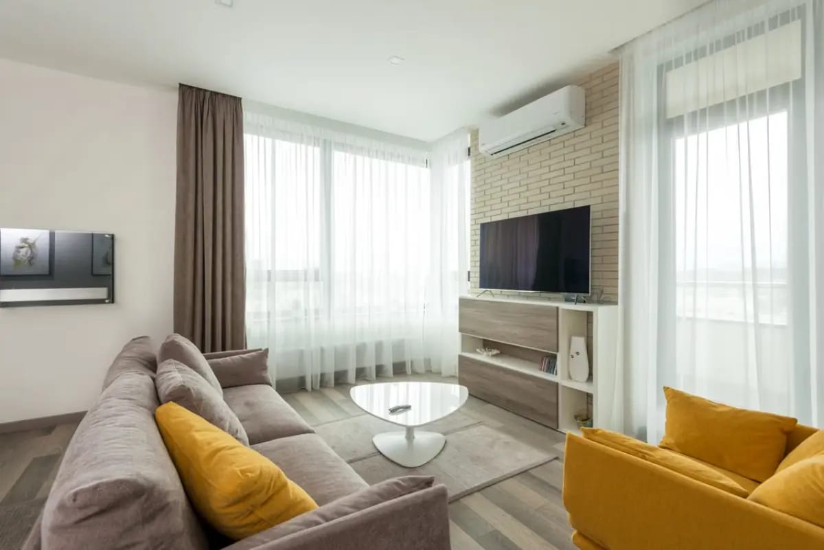 Cozy living room with couches, TV set, and air conditioner interior unit on the wall.