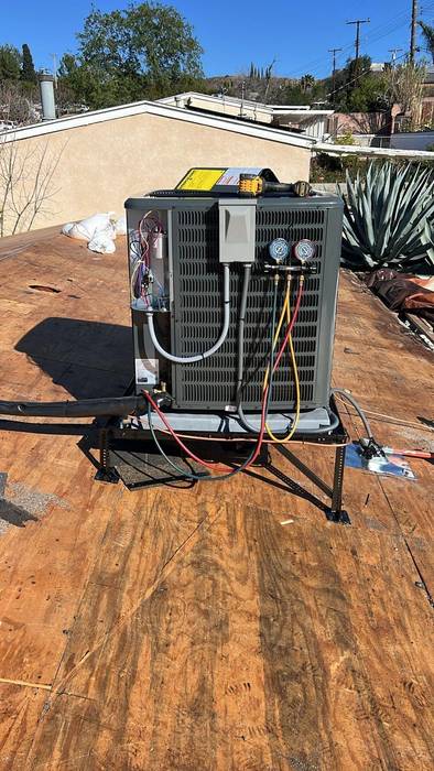 Exterior unit of an HVAC system with gauges and multi-colored cablings outside a home in Oahu.